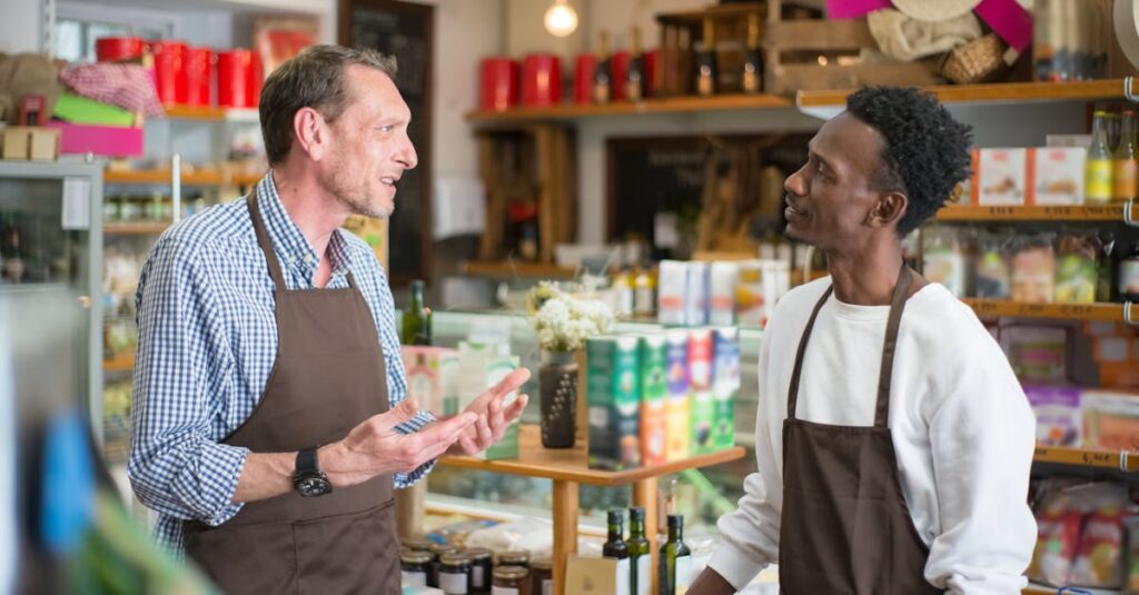 Two colleagues in aprons conversing in a grocery store setting, AI retail trends